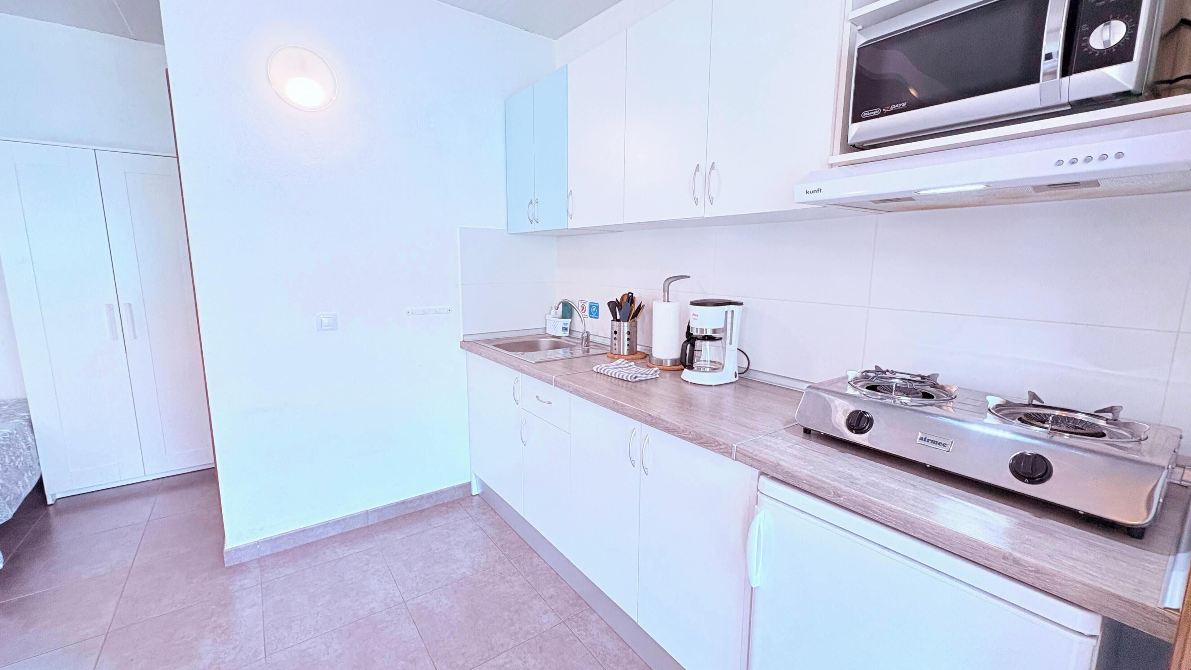 A modern kitchen with white cabinets, a stainless steel stove, and a microwave.
