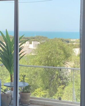 Un balcó amb vista al mar i vegetació.