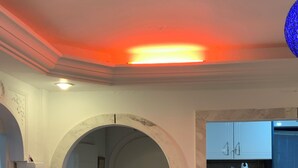 Um espaço compacto com cozinha, piso de mármore e porta que dá para outro cômodo.