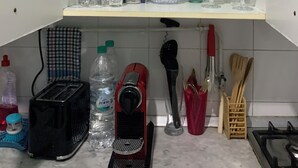 Uma cozinha com armários brancos, uma torradeira, um bebedouro e diversos utensílios de cozinha.