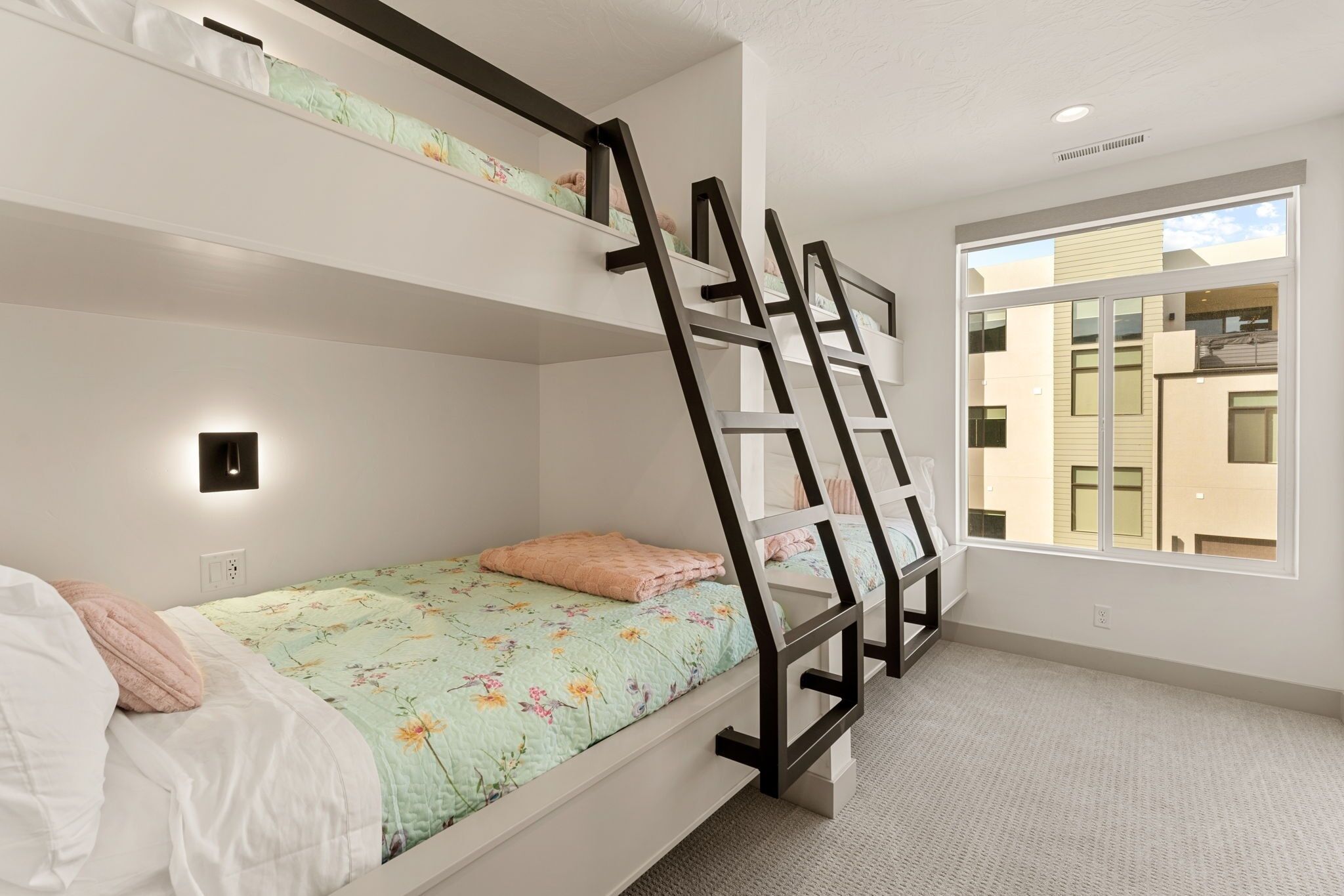 A bunk bed room with a window, a wall-mounted light, and a visible power outlet.