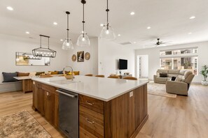 A spacious kitchen with a central island, wooden cabinets, and pendant lighting. - Sunrise Escape 7 Bedroom Home (St. George)