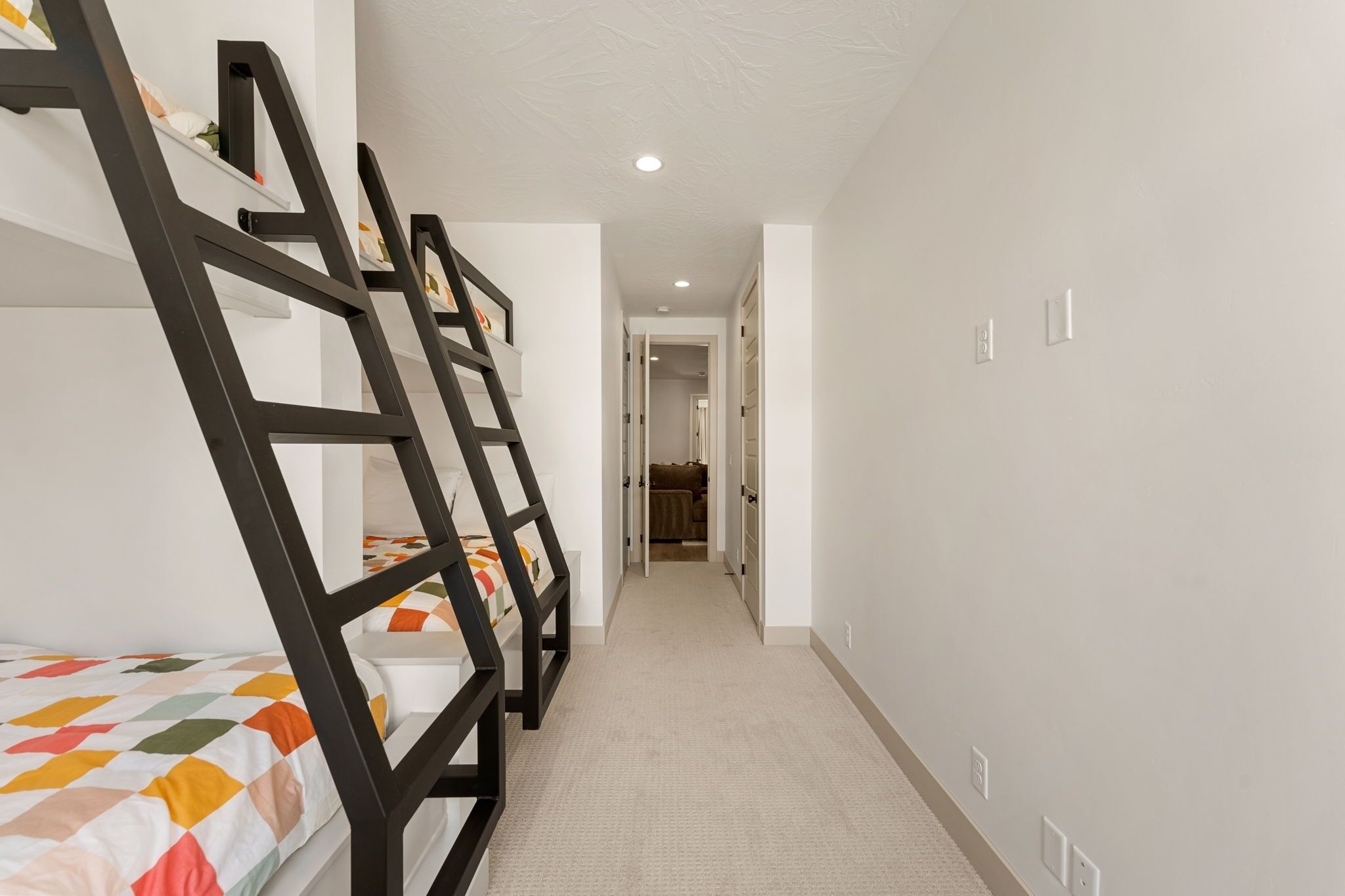 A narrow hallway with bunk beds on one side and a door leading to another room.