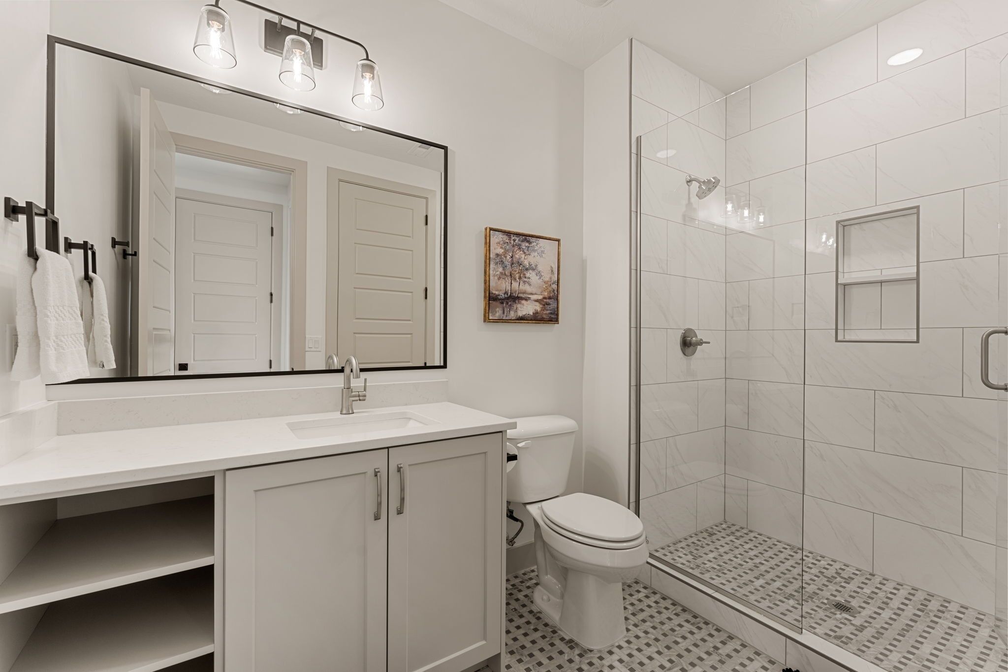 A modern bathroom with a white sink, toilet, and shower.