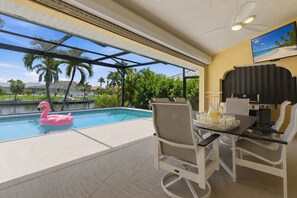 Ein Pool mit einem rosa Flamingo-Schwimmpfad, einem Grill und einem Tisch mit Getränken.