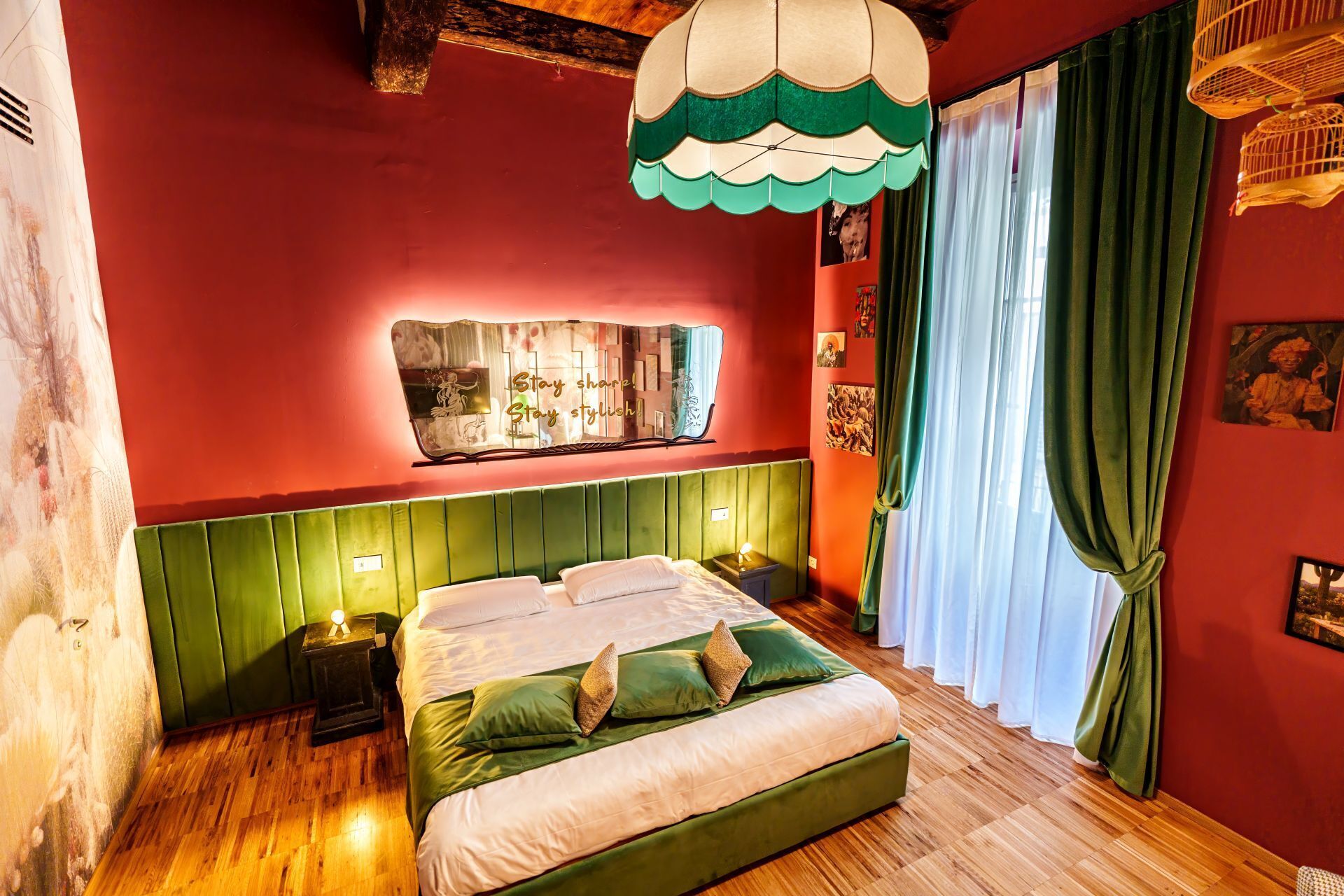 Una habitación con cama, mesita de noche, espejo en la pared y ventana con cortinas.
