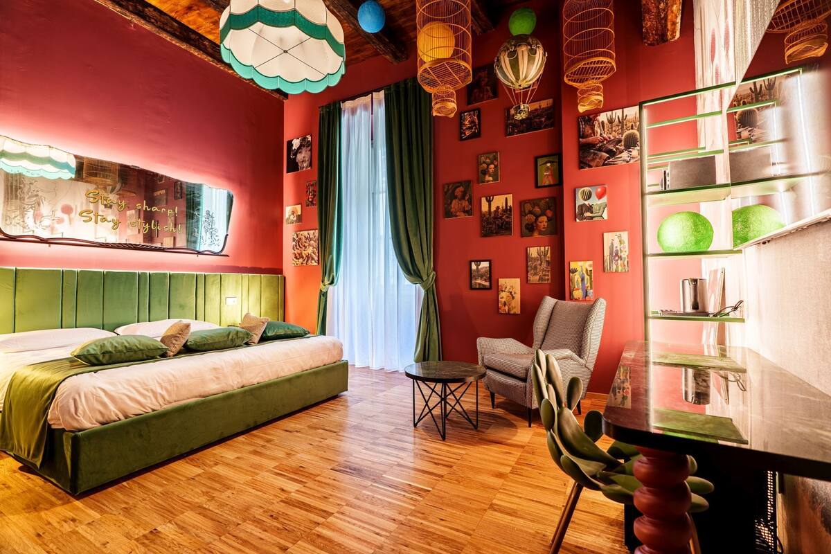 Ein Zimmer mit einem Bett, einem Sessel, einem Tisch und einem Regal mit Dekoration.