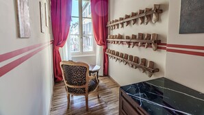 Une pièce avec un plancher en bois, une chaise dotée d’un coussin à motif léopard, une table avec un plateau en marbre noir et un porte-chaussures fixé au mur.