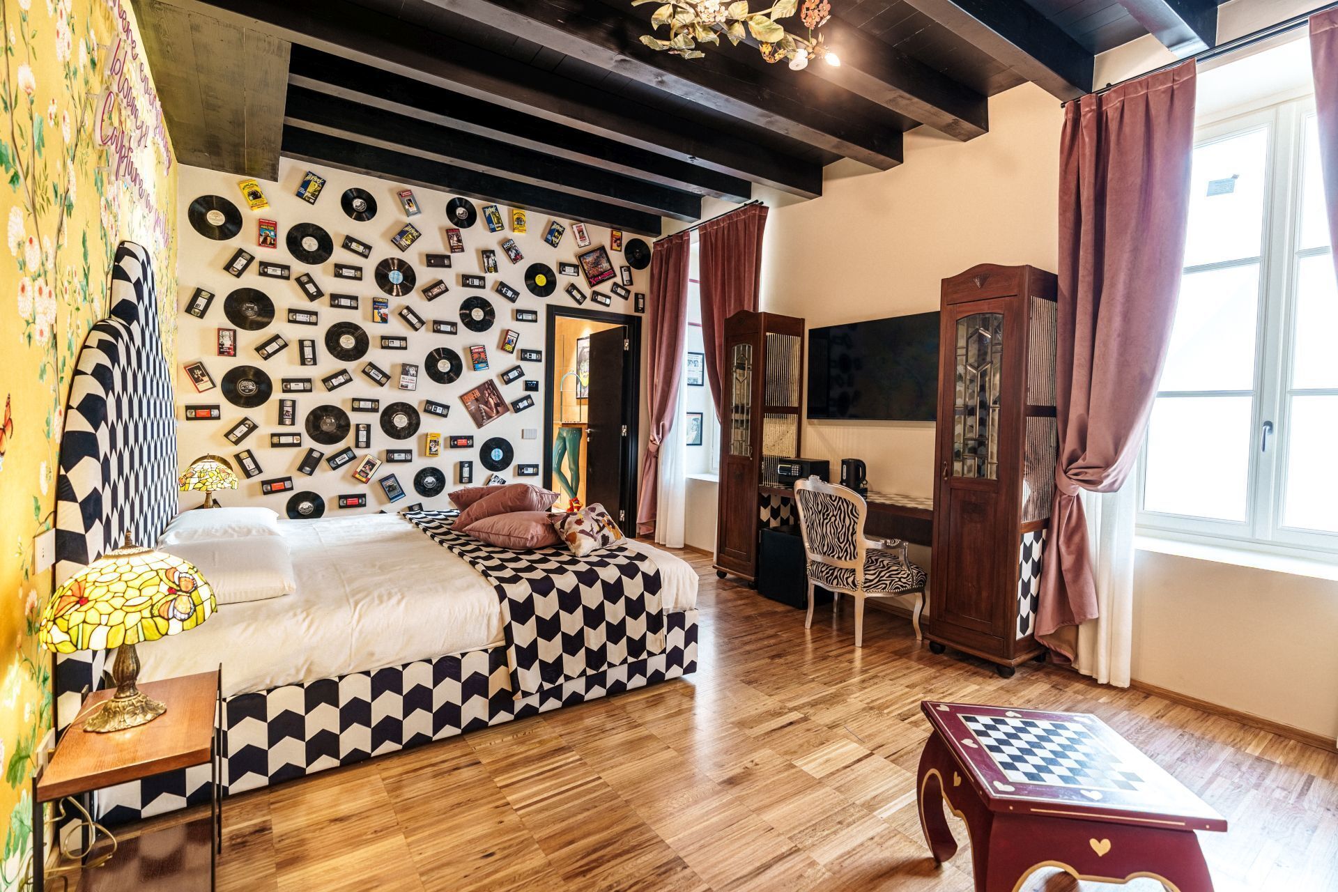 Ein Zimmer mit einem Bett, einem Schreibtisch, einem Stuhl, einem Schrank und einer Wand, die mit Schallplatten dekoriert ist.