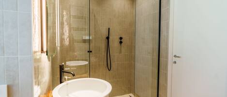 A modern bathroom with a glass-enclosed shower, a white sink, and a wooden vanity.