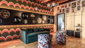 Un salon moderne avec un canapé, deux poufs, un mur orné de miroirs ronds et un plafond en bois.