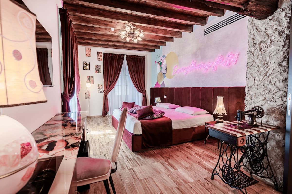 Ein Schlafzimmer mit Bett, Schreibtisch, Stuhl, Nähmaschine und einer Neonreklame.