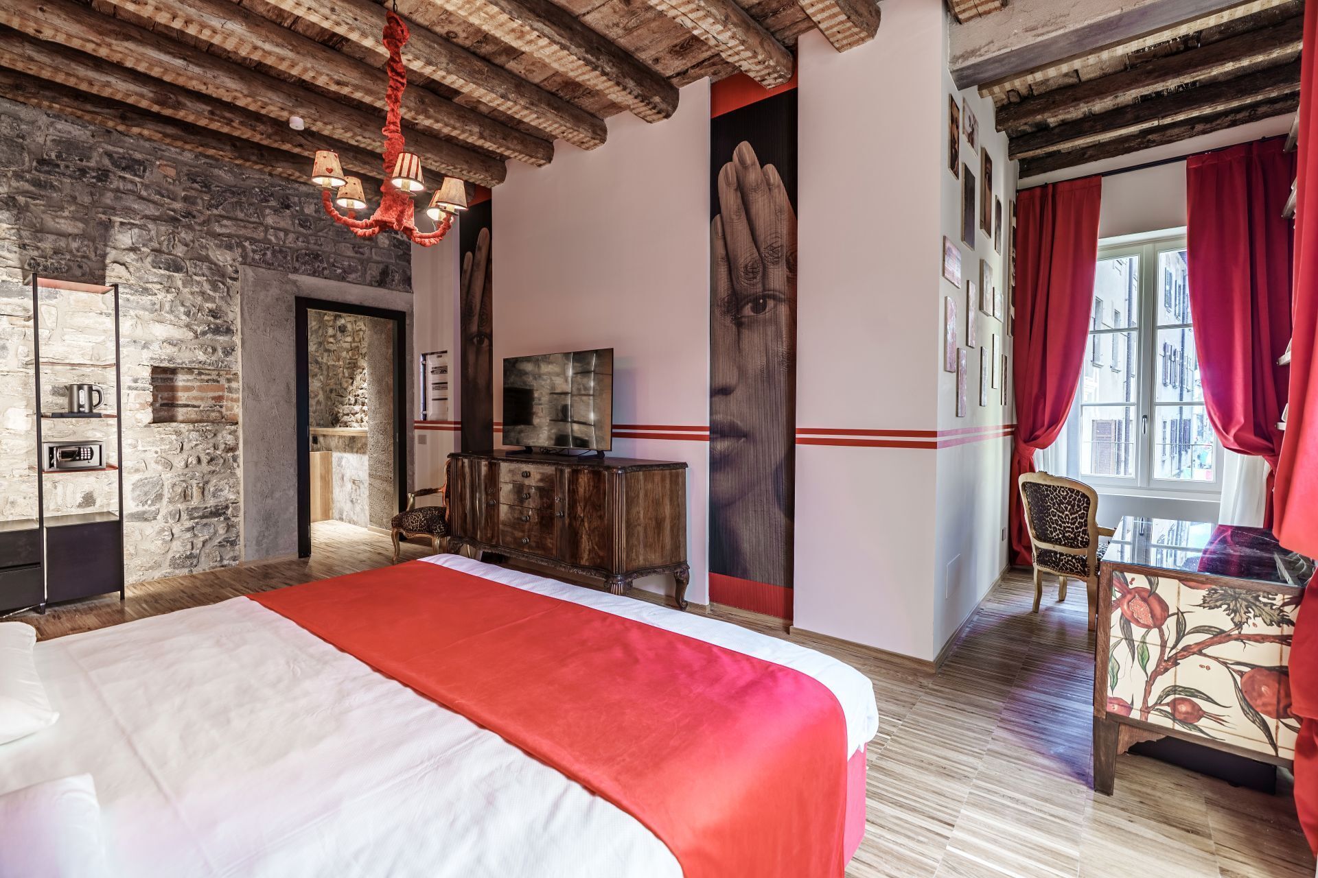Une chambre avec un lit, une télévision, un mur en pierre et un rideau rouge.