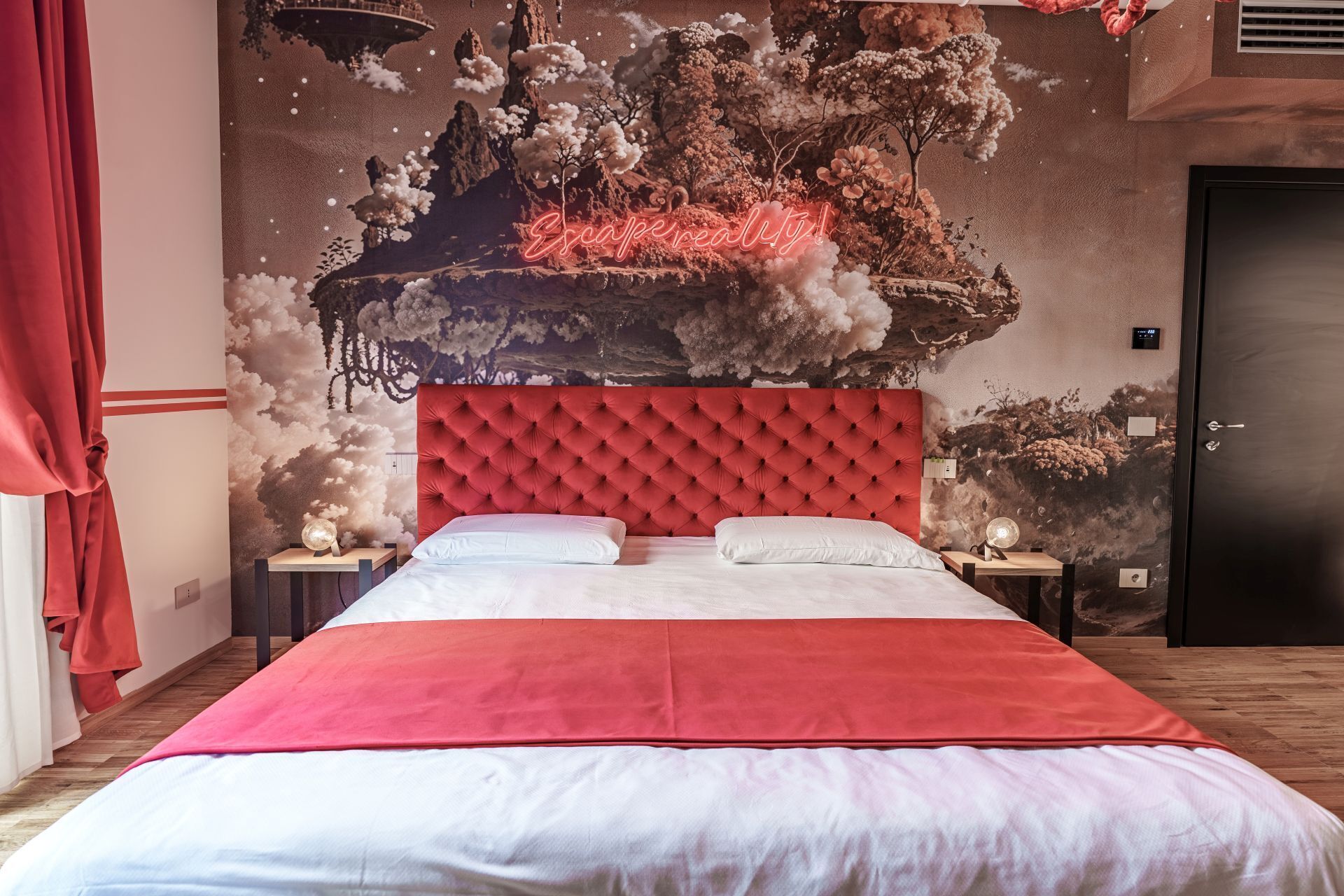 Een slaapkamer met een rode, gebobbelde hoofdbord, een groot bed met witte beddengoed, en een muurschildering van een zwevend eiland met wolken.