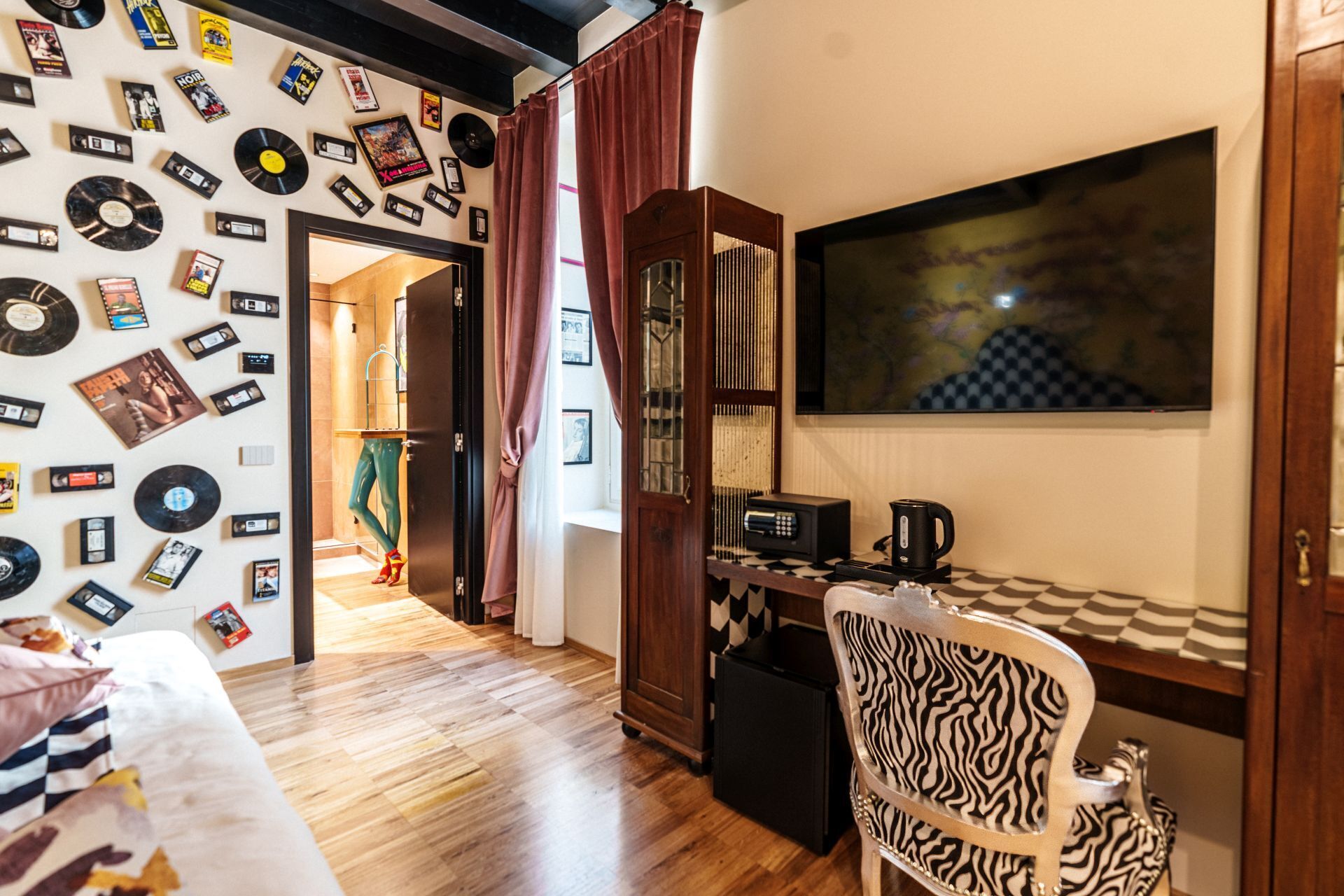 A room with a wall decorated with vinyl records, a wooden cabinet, a zebra-patterned chair, and a large mirror.