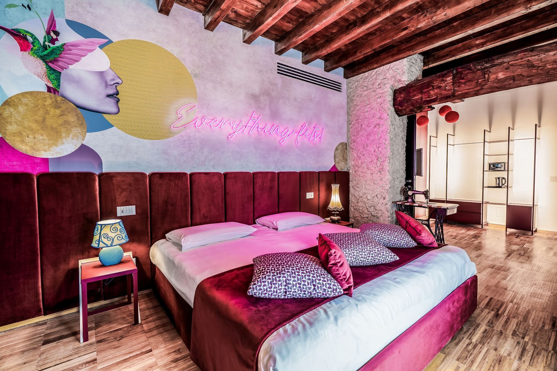 Ein modernes Schlafzimmer mit einem großen Bett, einer Neonleuchtreklame und einer außergewöhnlichen Wandmalerei.