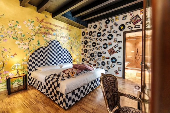 Un dormitorio con cabecera de cuadros, papel tapiz floral y una pared de discos de vinilo.