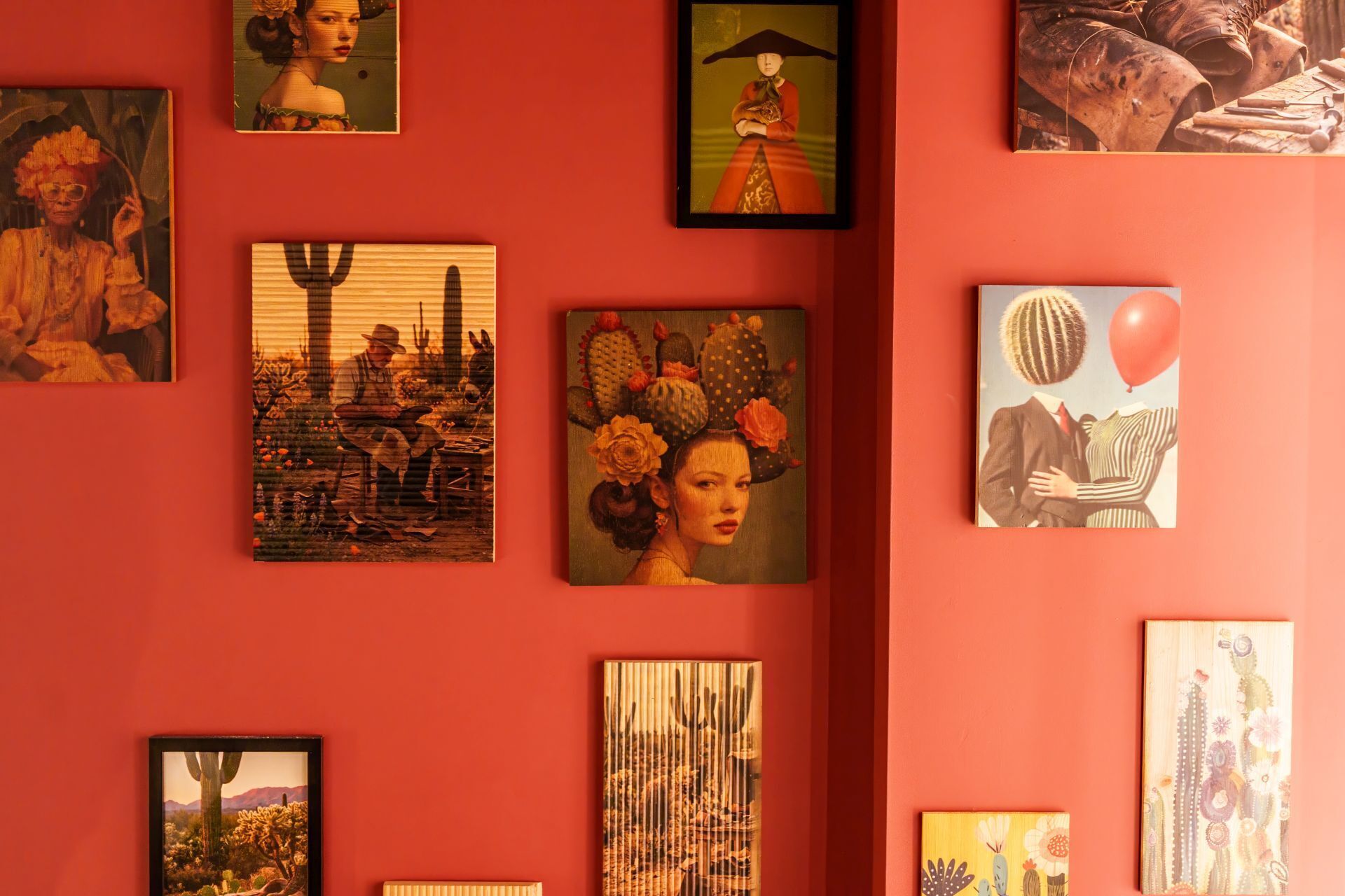 Eine Wand mit verschiedenen gerahmten Kunstwerken, darunter Porträts und Landschaftsbilder.