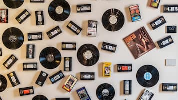 Eine Ansammlung von Schallplatten und Kassettentapes, die an einer Wand verteilt liegen.