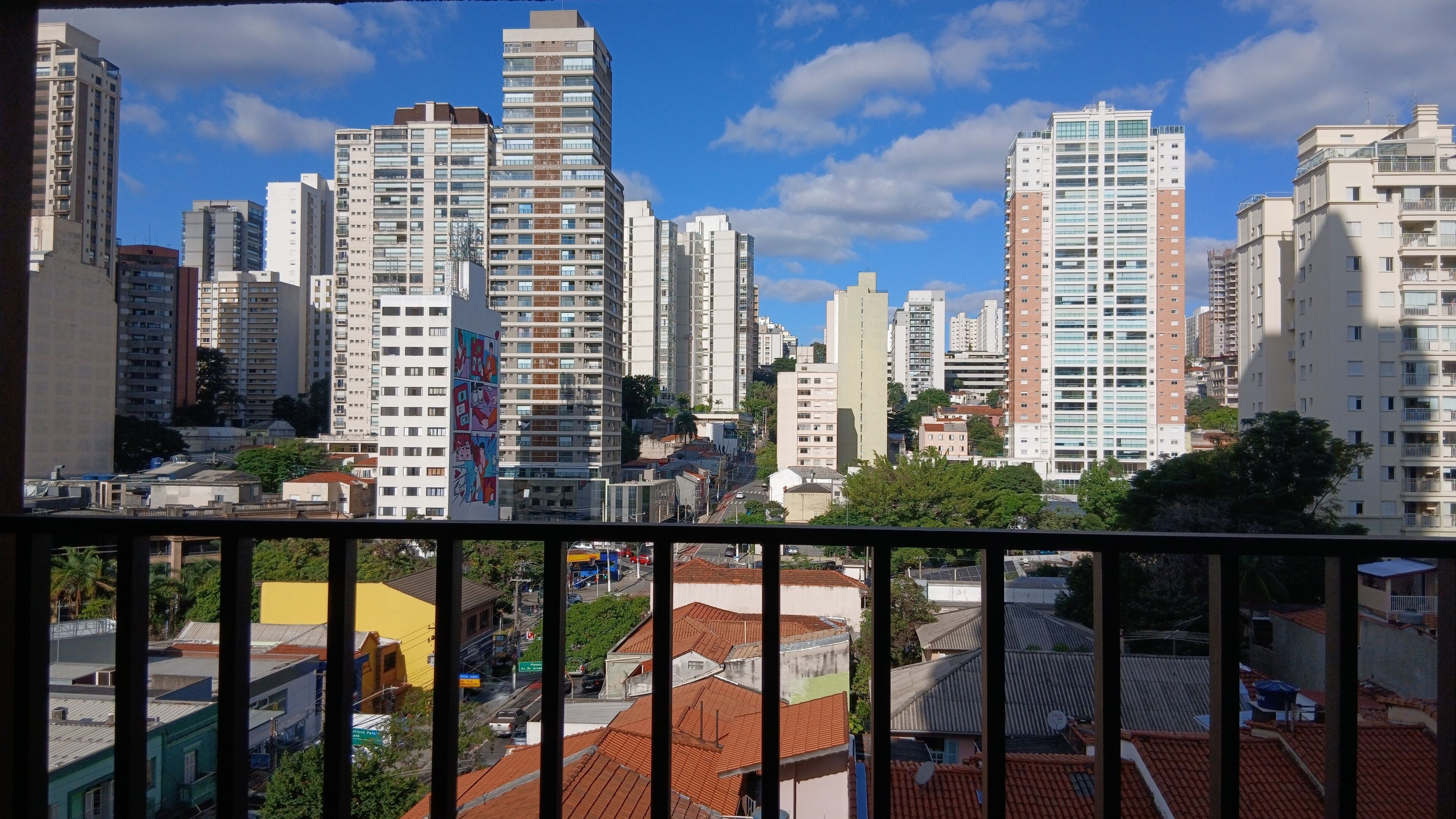 Un paisaje urbano con edificios altos, cielo despejado y barandilla de balcón.