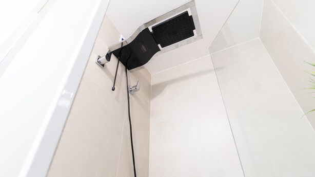 Une douche avec un tuyau noir et un panneau de commande.