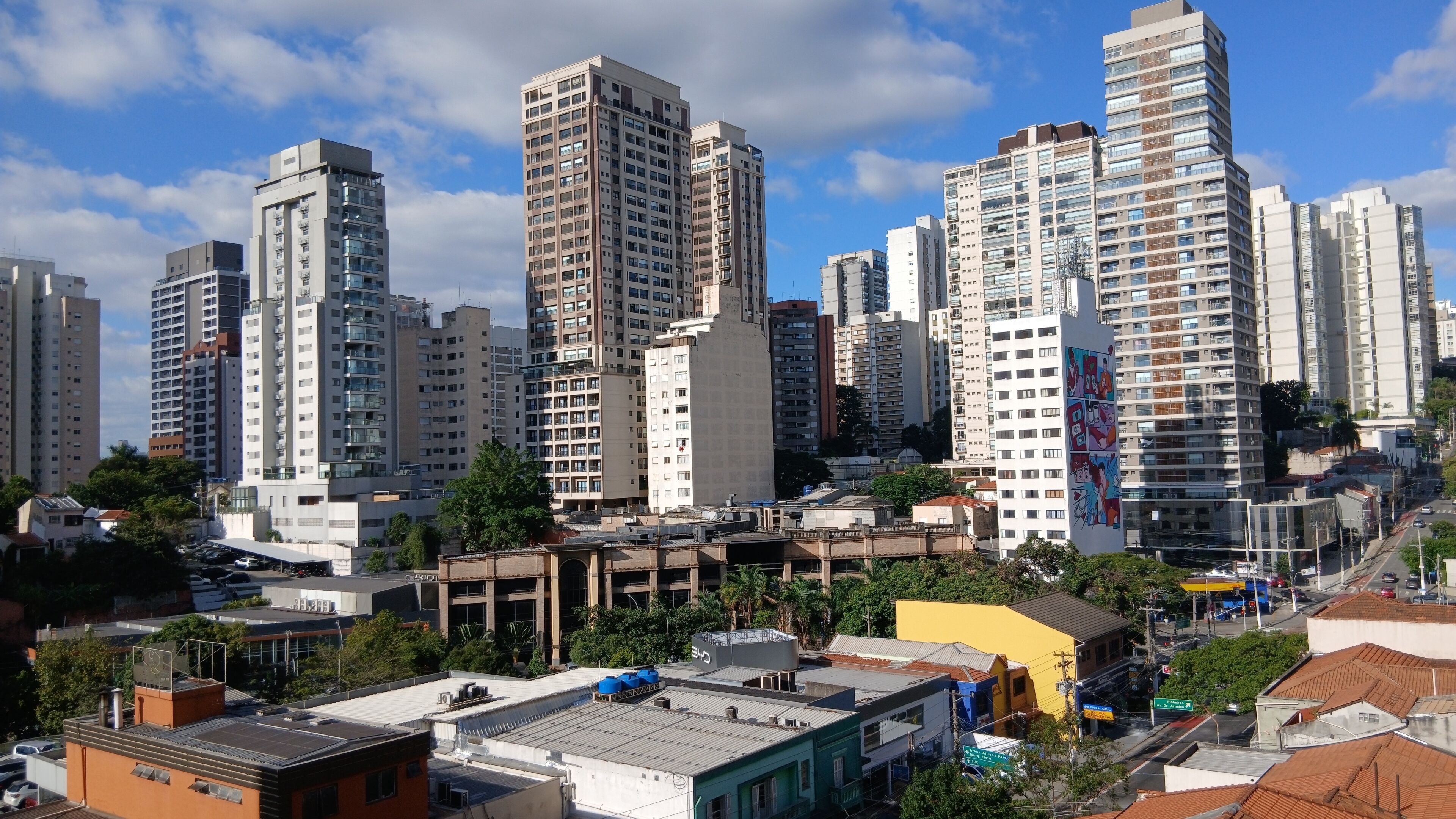 Un paisaje urbano con edificios altos, una mezcla de construcciones residenciales y comerciales, y un cielo despejado.