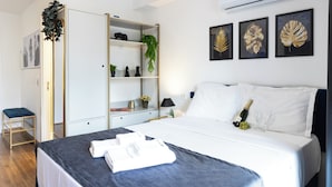 Una habitación de hotel con cama, armario, escritorio y una pared decorada con cuadros.