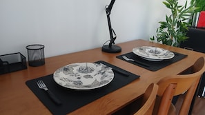 Una mesa de comedor con dos platos, individuales negros, un tenedor y una lámpara.