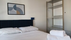 A hotel room with a bed, a wardrobe, and a wall-mounted abstract artwork. - Vista incrível com AC e academia (São Paulo)