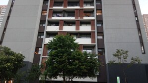 Un edificio de varios pisos con balcones y un árbol en primer plano.