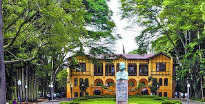 Un edificio amarillo con ventanas de arco y una estatua central.