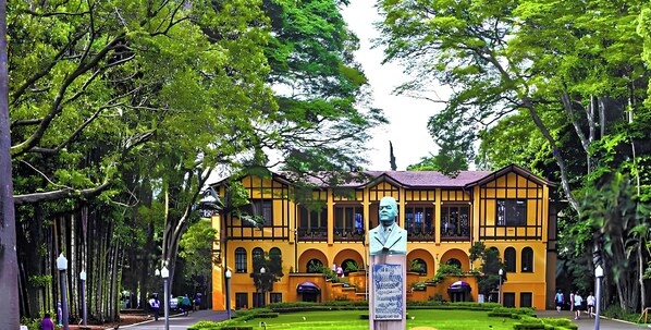 A yellow building with arched windows and a central statue. - Vista incrível com AC e academia (São Paulo)