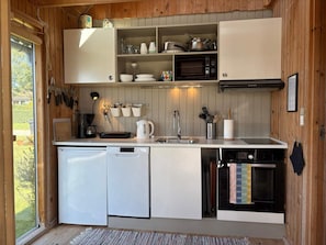 Eine kompakte Küche mit Geschirrspüler, Backofen, Mikrowelle und kleinem Spülbecken.