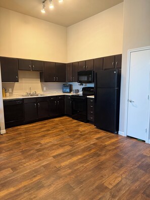 A kitchen with dark cabinets, a microwave, a refrigerator, and a dishwasher.