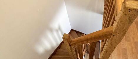 Un escalier en bois, doté d’une rampe, mène à un palier dont le sol est également en bois.