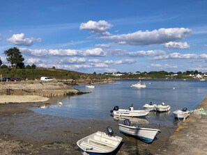 A calm waterfront with several boats docked, a clear sky, and a distant shoreline with houses. - Renovated farmhouse dating from 1821 (SAINTE HELENE)