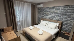 A bedroom with a bed, a wooden nightstand, a brick-patterned wall, and a ceiling light. - Perla Cozy Apartment (Scutari)
