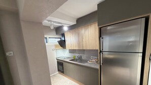 A kitchen with wooden cabinets, a stainless steel refrigerator, and a built-in oven. - Perla Cozy Apartment (Scutari)