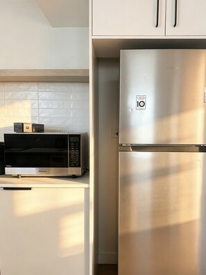 Eine Küche mit einem Edelstahl-Kühlschrank, einer Mikrowelle und einem Schrank.