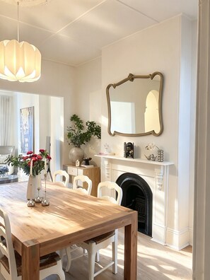 A dining room with a wooden table, white chairs, a fireplace, and a large mirror on the wall. - Central Terrace Near Sydney Uni, Broadway & The City (Forest Lodge)