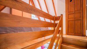Uma escada de madeira leva a um quarto com uma grande porta de madeira e um claraboia.