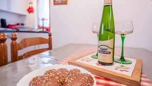 Uma mesa de jantar com uma garrafa de vinho branco, duas taças de vinho e um prato de doces decorados.