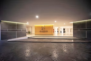 Un hall d’hôtel moderne avec un comptoir d’accueil portant l’inscription « HORIZON », un espace vaste doté d’un sol en pierre et un design minimaliste.