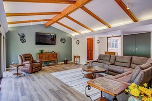 Ein geräumiges Wohnzimmer mit einem großen Ecksofa, einem Ledersessel und einem Couchtisch aus Holz.