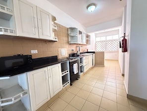 A kitchen with white cabinets, a black countertop, a stove, and a fire extinguisher. - New, Villa With a View, new Design- Pics in a few Days (Mombasa)
