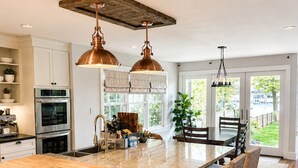 Una cocina con una isla grande, sillas de madera e iluminación colgante.
