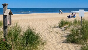 Una playa con una estructura de madera, un letrero y gente relajándose.