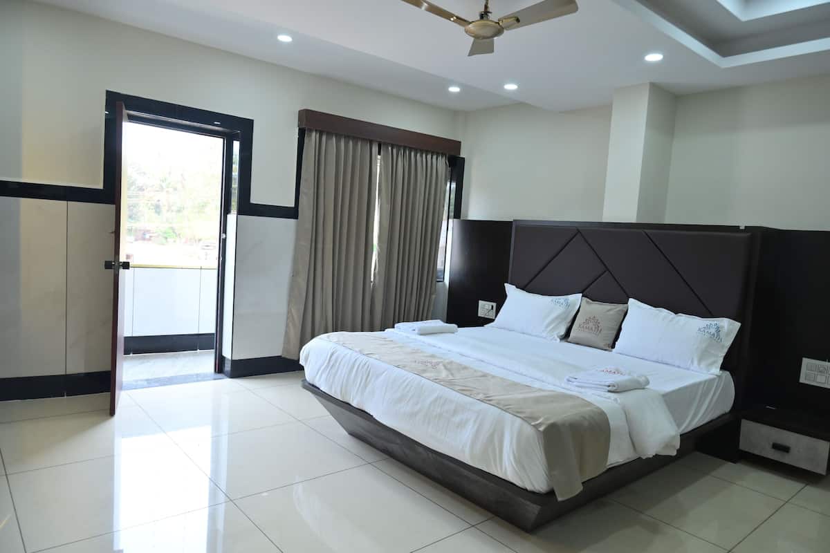 Una habitación de hotel con una cama grande, un ventilador de techo, un armario y una puerta que da a un balcón.