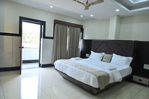 Una habitación de hotel con una cama grande, un ventilador de techo, un armario y una puerta que da a un balcón.
