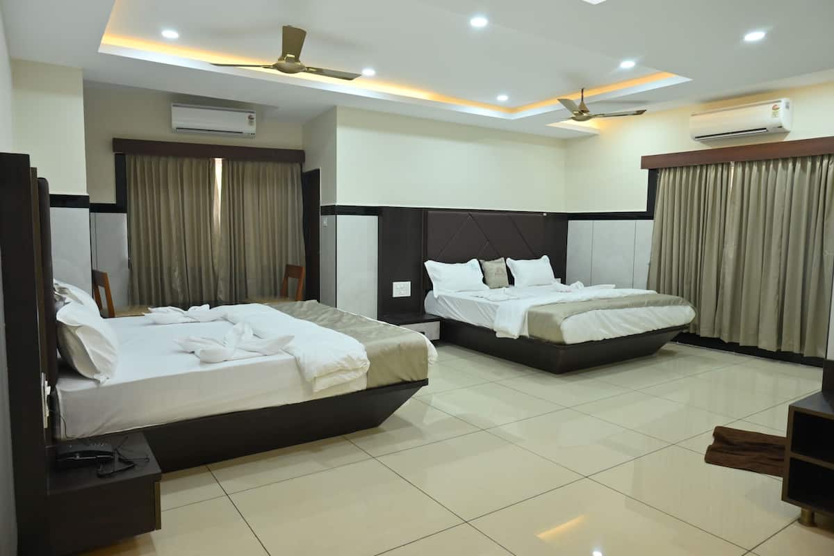 Habitación de hotel con dos camas, ventiladores de techo, unidades de aire acondicionado y piso de baldosas.